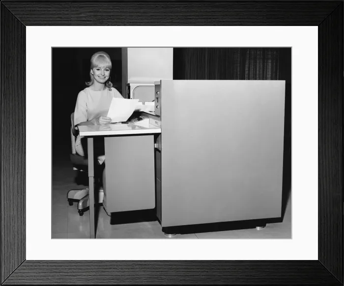 Framed Print : Woman holding paper and sitting at desk Framed Print : Woman holding paper and sitting at desk