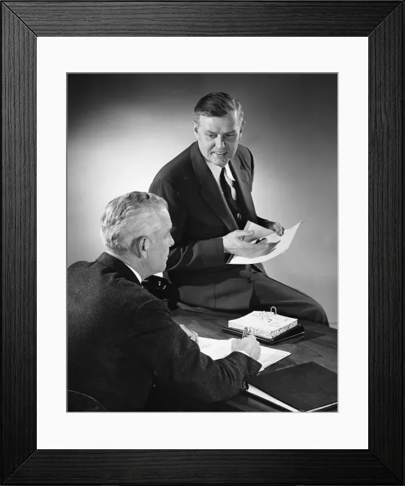 Framed Print : Two men talking, one sitting on desk Framed Print : Two men talking, one sitting on desk