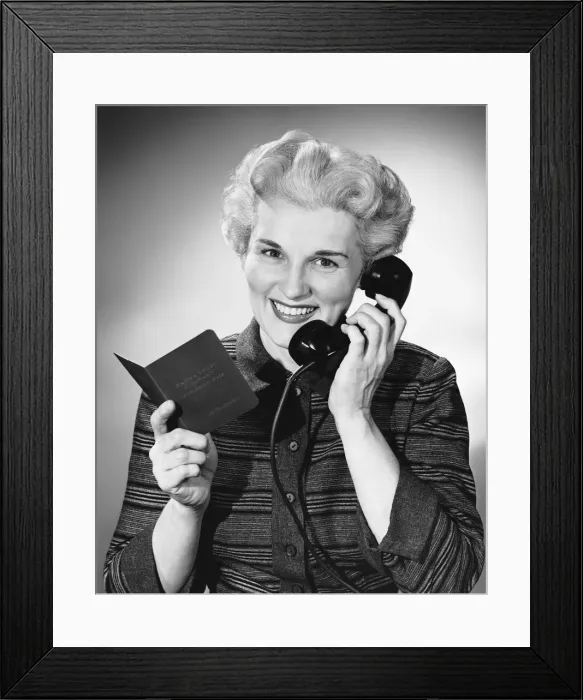 Framed Print : Woman using phone, holding small book in one hand Framed Print : Woman using phone, holding small book in one hand