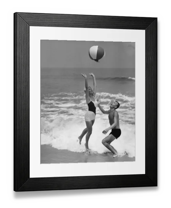 Framed Print : Young couple playing with beach ball at waters edge Framed Print : Young couple playing with beach ball at waters edge