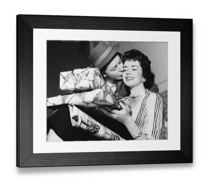 Framed Print : Husband kissing wife with armful of gifts Framed Print : Husband kissing wife with armful of gifts