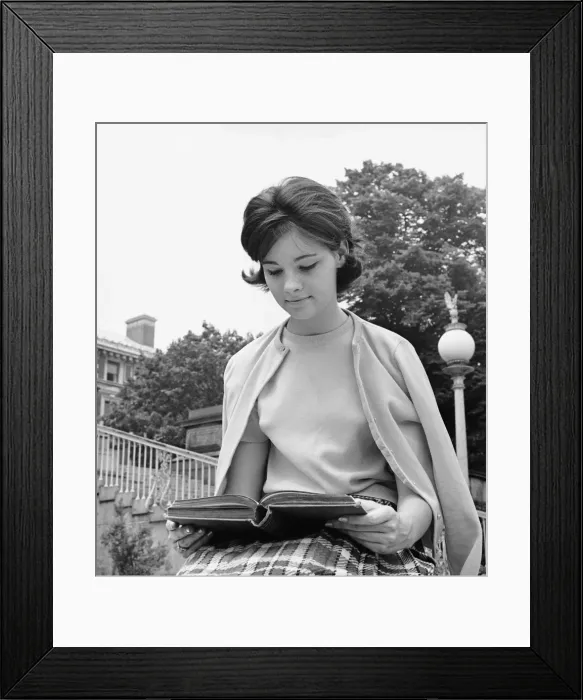 Framed Print : Female student sitting outdoors, reading book Framed Print : Female student sitting outdoors, reading book
