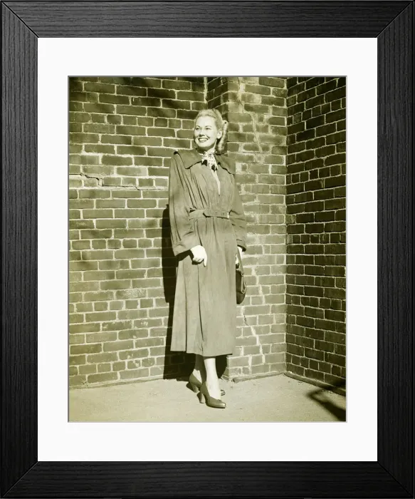 Framed Print : Woman wearing mackintosh standing at brick wall outdoors, (B&W) Framed Print : Woman wearing mackintosh standing at brick wall outdoors, (B&W)