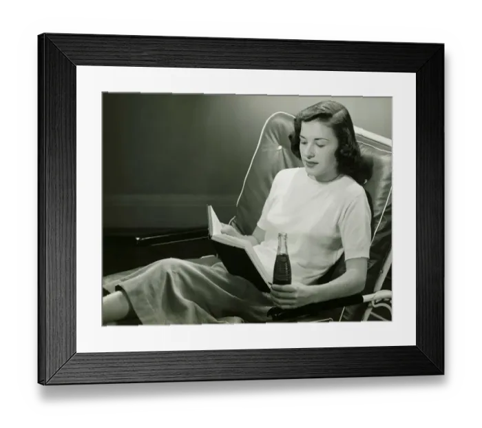 Framed Print : Woman with bottle of beverage, reading book, (B&W) Framed Print : Woman with bottle of beverage, reading book, (B&W)