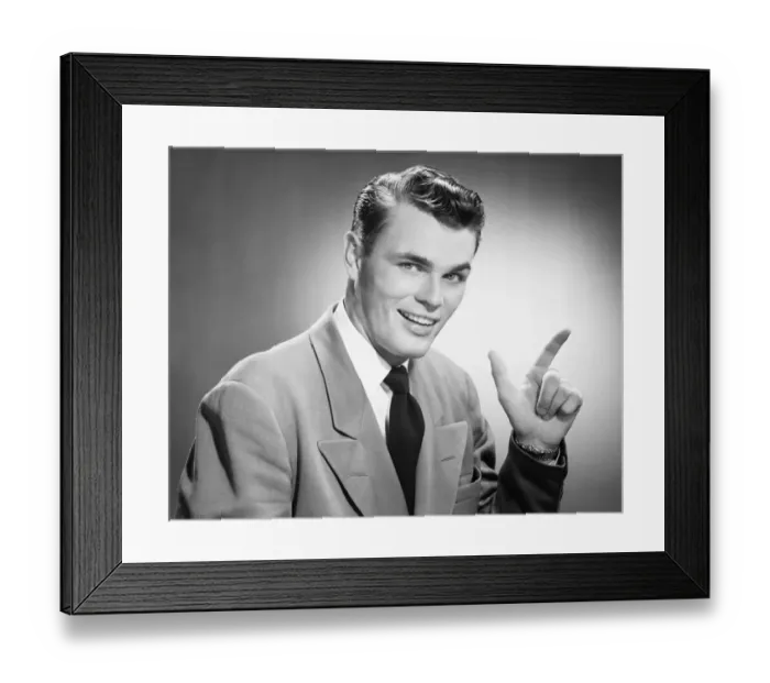 Framed Print : Young man pointing in studio, (B&W), (Close-up), (Portrait) Framed Print : Young man pointing in studio, (B&W), (Close-up), (Portrait)