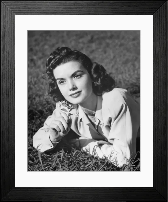 Framed Print : Young woman lying on grass, holding flower, (B&W), (Portrait) Framed Print : Young woman lying on grass, holding flower, (B&W), (Portrait)