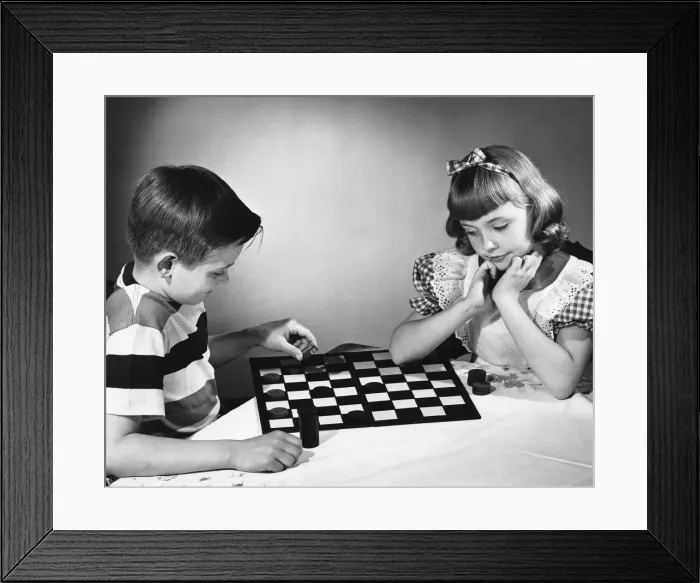 Framed Print : Brother and sister playing checkers at table Framed Print : Brother and sister playing checkers at table