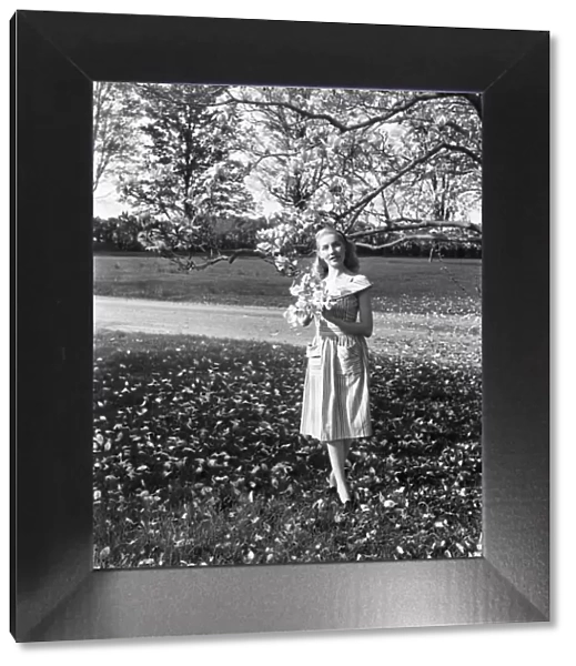 Portrait of young woman standing under magnolia tree in park