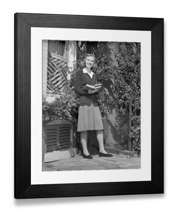 Framed Print : Female student holding book in back yard, portrait Framed Print : Female student holding book in back yard, portrait