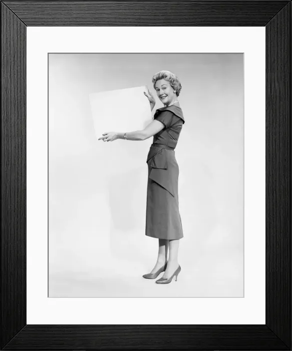 Framed Print : Woman holding blank piece of paper, portrait, studio shot
