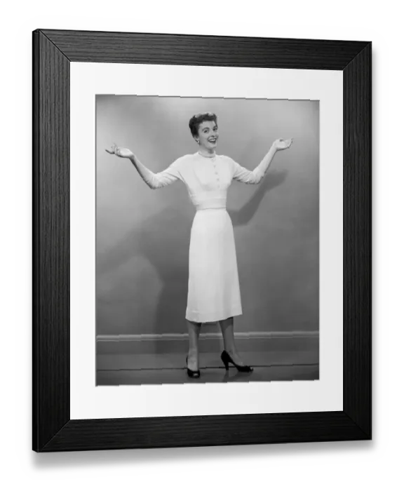 Framed Print : Woman with arms raised in studio, portrait Framed Print : Woman with arms raised in studio, portrait