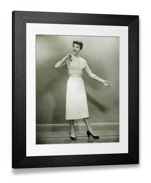 Framed Print : Woman in white dress pointing to herself in studio, (B&W), portrait Framed Print : Woman in white dress pointing to herself in studio, (B&W), portrait