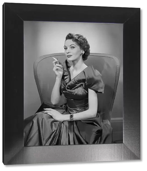 Woman smoking cigarette in armchair, portrait