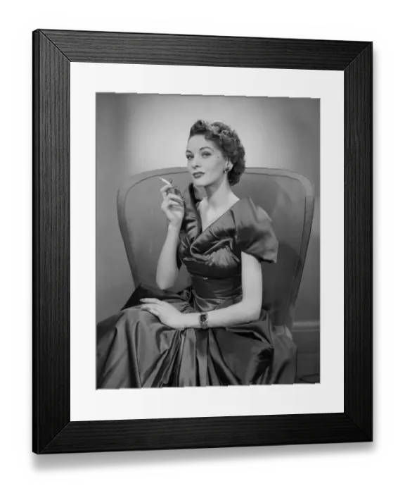Framed Print : Woman smoking cigarette in armchair, portrait