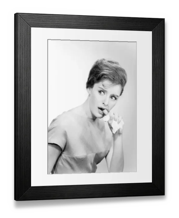 Framed Print : Studio shot of young woman biting finger Framed Print : Studio shot of young woman biting finger