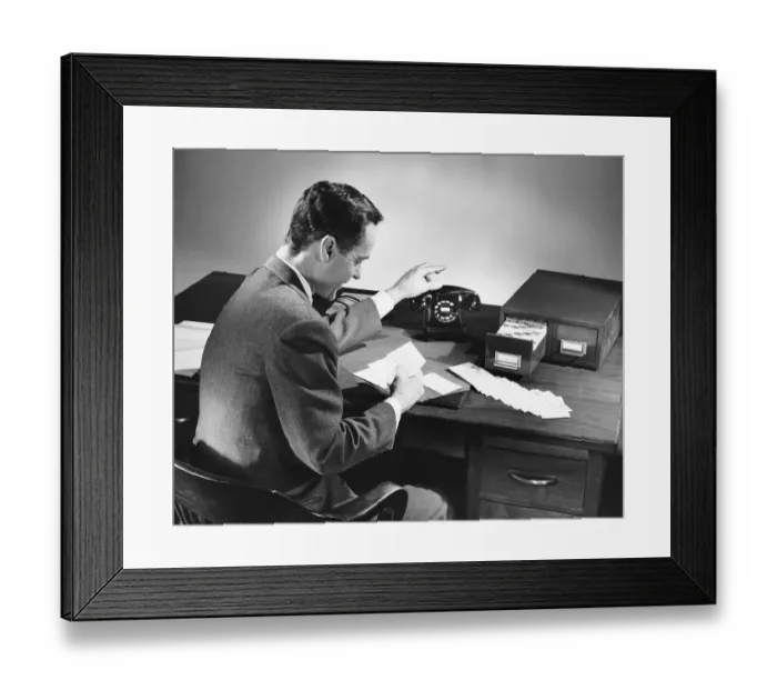 Framed Print : Man reaching for phone while reading card Framed Print : Man reaching for phone while reading card