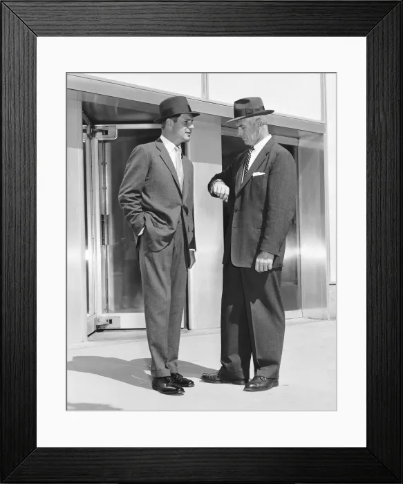 Framed Print : Two men standing, one checking watch Framed Print : Two men standing, one checking watch