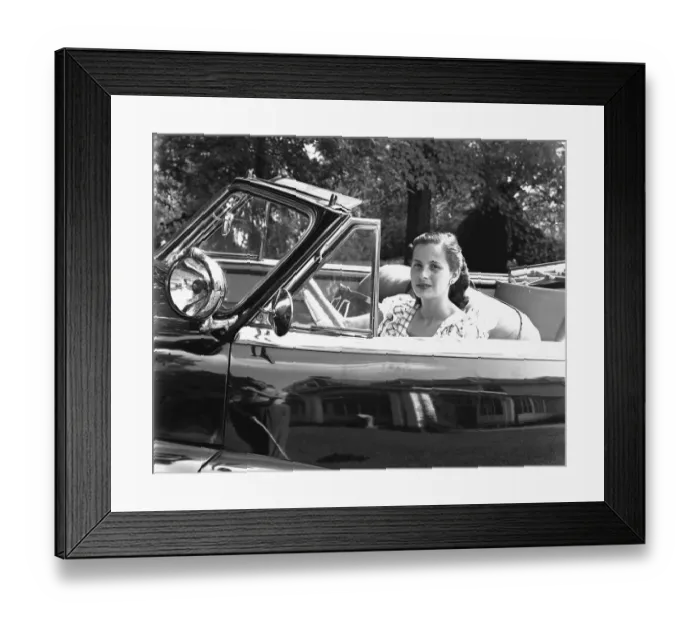 Framed Print : Young woman sitting in convertible car, (B&W), portrait