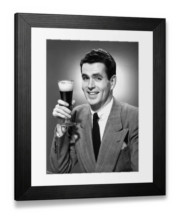 Framed Print : Man holding glass of beer in studio, (B&W), portrait Framed Print : Man holding glass of beer in studio, (B&W), portrait
