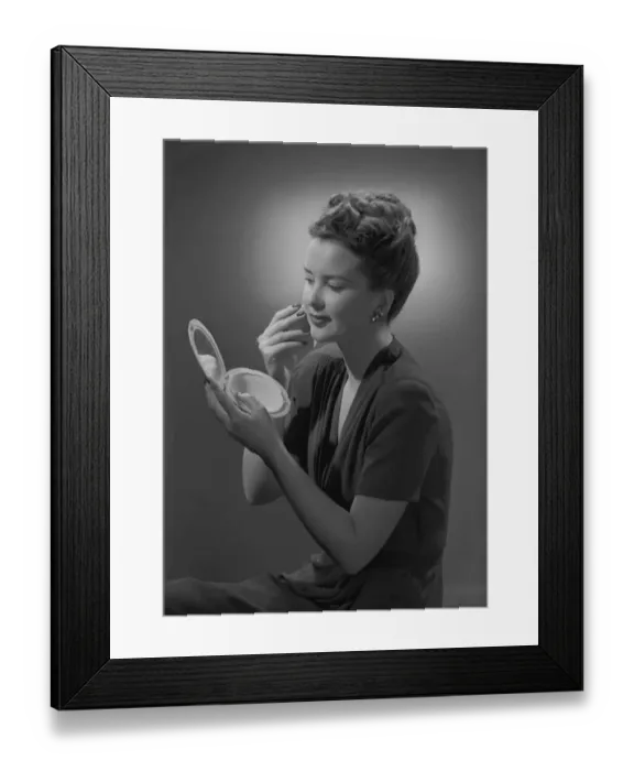 Framed Print : Studio shot of young woman applying make-up Framed Print : Studio shot of young woman applying make-up