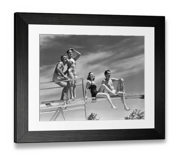 Framed Print : Two couples sitting on springboard, (B&W), low angle view Framed Print : Two couples sitting on springboard, (B&W), low angle view