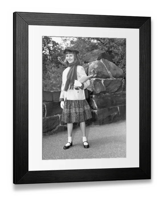Framed Print : Girl (12-13) holding book, posing by wall, (B&W), portrait