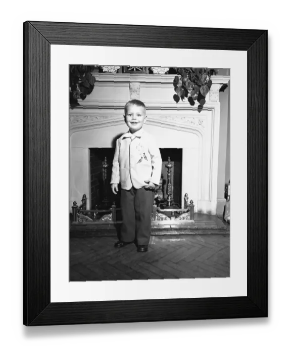 Framed Print : Boy (3-4) standing by fireplace, (B&W), portrait