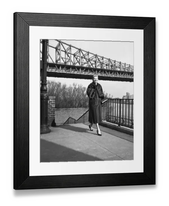 Framed Print : Woman wearing fur coat, standing by bridge (B&W) Framed Print : Woman wearing fur coat, standing by bridge (B&W)