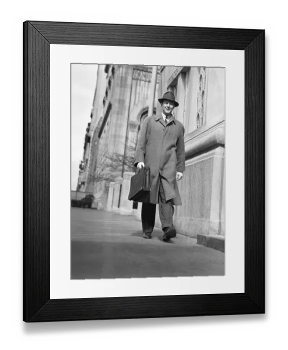 Framed Print : Man in overcoat and hat walking on sidewalk, (B&W), low angle view Framed Print : Man in overcoat and hat walking on sidewalk, (B&W), low angle view
