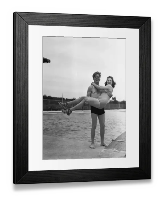Framed Print : Man lifting woman at pool edge, (B&W), portrait Framed Print : Man lifting woman at pool edge, (B&W), portrait