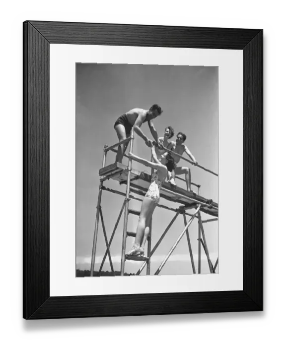 Framed Print : Two couples on springboard, (B&W), low angle view Framed Print : Two couples on springboard, (B&W), low angle view
