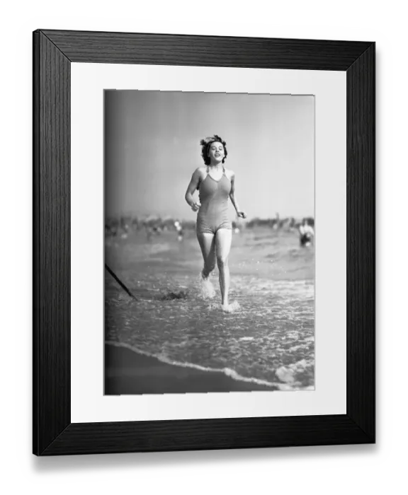 Framed Print : Woman in swimsuit running on shoreline, (B&W) Framed Print : Woman in swimsuit running on shoreline, (B&W)