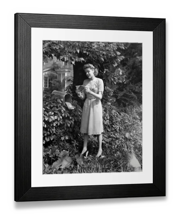 Framed Print : Woman standing at mailbox, looking at letters, (B&W) Framed Print : Woman standing at mailbox, looking at letters, (B&W)