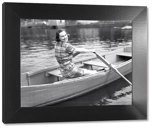 Woman rowing boat on lake, (B&W), portrait
