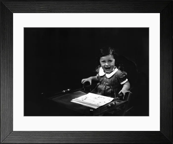 Framed Print : Girl (4-5) sitting in high chair, crying, (B&W) Framed Print : Girl (4-5) sitting in high chair, crying, (B&W)