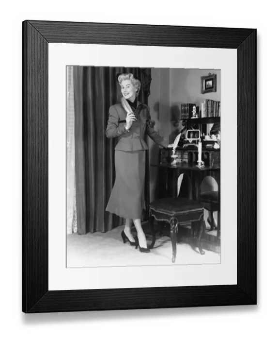 Framed Print : Elegant woman standing at desk in living room (B&W) Framed Print : Elegant woman standing at desk in living room (B&W)