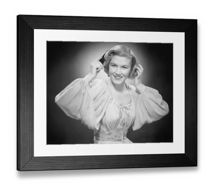 Framed Print : Woman in evening dress combing hair in studio (B&W), portrait Framed Print : Woman in evening dress combing hair in studio (B&W), portrait
