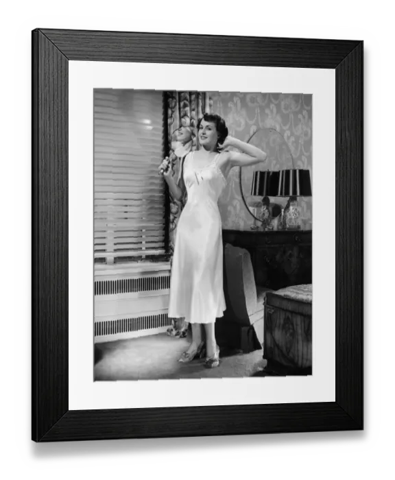Framed Print : Woman in underskirt standing in bedroom (B&W) Framed Print : Woman in underskirt standing in bedroom (B&W)