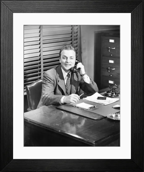 Framed Print : Businessman talking on phone at desk (B&W) Framed Print : Businessman talking on phone at desk (B&W)