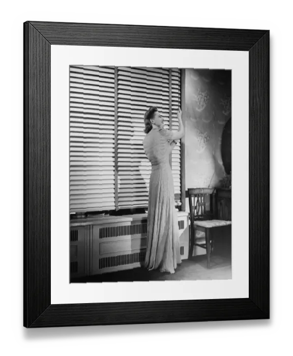 Framed Print : Woman adjusting widow blind, (B&W) Framed Print : Woman adjusting widow blind, (B&W)