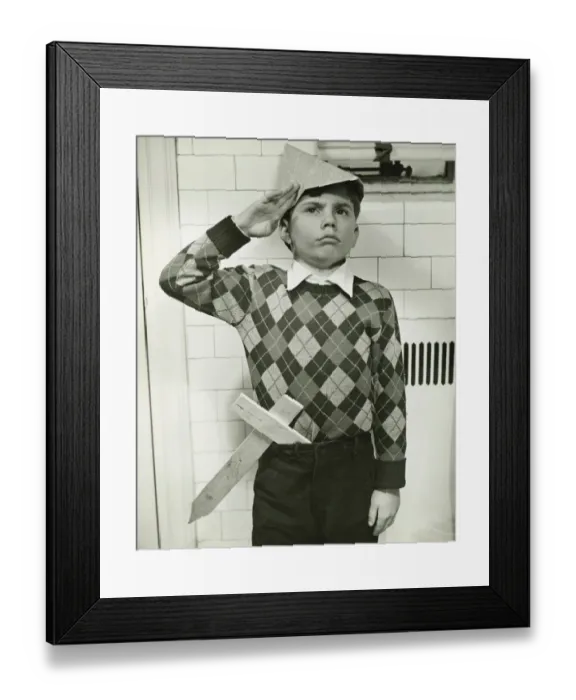 Framed Print : Boy (8-9) with wooden sword saluting indoors, (B&W) Framed Print : Boy (8-9) with wooden sword saluting indoors, (B&W)