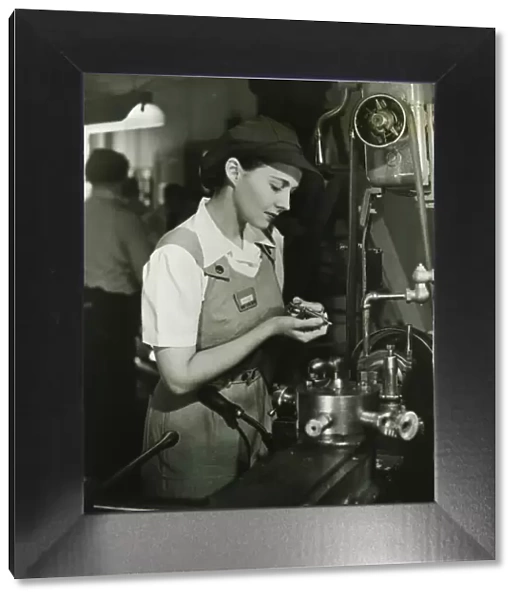 Young woman in overalls working by lathe in factory, (B&W)