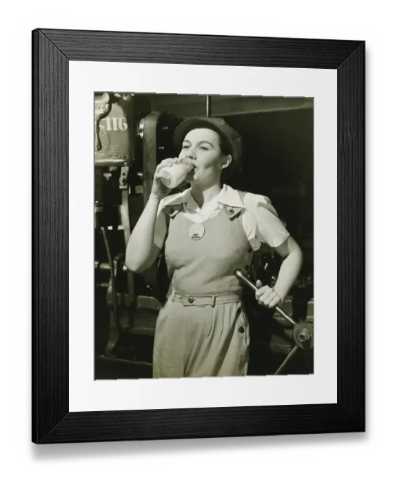 Framed Print : Young woman in overalls standing by lathe in factory, drinking milk, (B&W) Framed Print : Young woman in overalls standing by lathe in factory, drinking milk, (B&W)