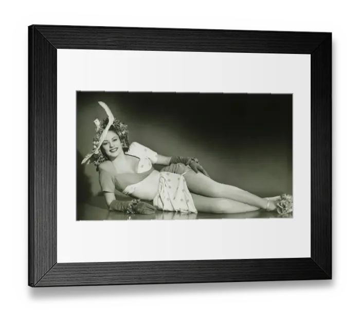 Framed Print : Young woman in fashionable hat lying down in studio, (B&W) Framed Print : Young woman in fashionable hat lying down in studio, (B&W)