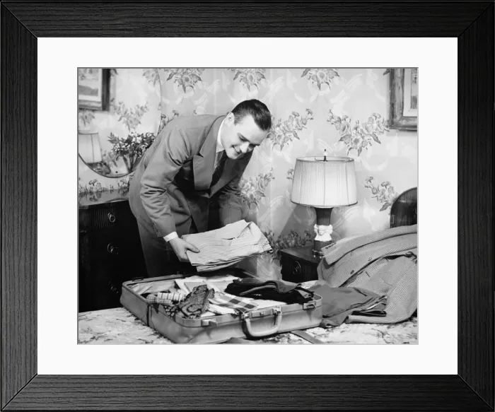Framed Print : Man packing suitcase in bedroom (B&W) Framed Print : Man packing suitcase in bedroom (B&W)