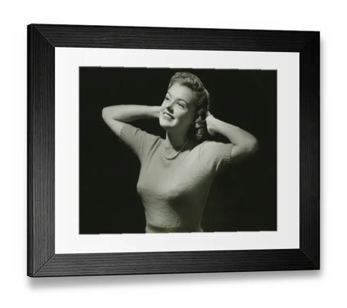 Framed Print : Young woman with hands behind head in studio, (B&W), close-up Framed Print : Young woman with hands behind head in studio, (B&W), close-up