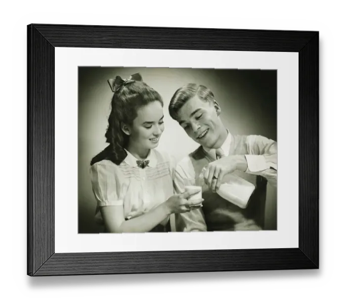 Framed Print : Young couple sharing bottle of milk, smiling, (B&W), close-up Framed Print : Young couple sharing bottle of milk, smiling, (B&W), close-up