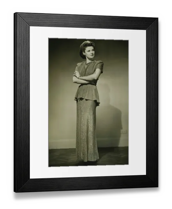 Framed Print : Young woman in fashionable dress standing in studio, (B&W) Framed Print : Young woman in fashionable dress standing in studio, (B&W)