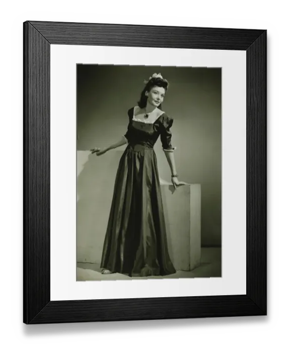 Framed Print : Young woman in evening dress leaning against low wall indoors, (B&W) Framed Print : Young woman in evening dress leaning against low wall indoors, (B&W)