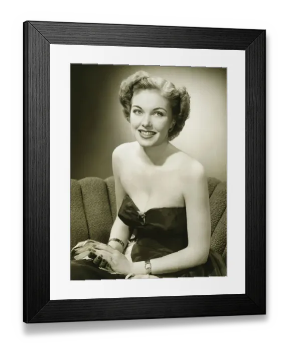 Framed Print : Woman in evening gown sitting on sofa, (B&W), (Portrait) Framed Print : Woman in evening gown sitting on sofa, (B&W), (Portrait)